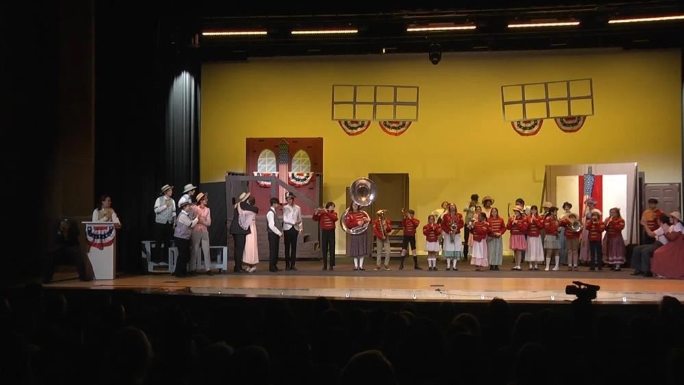 Students are standing with band uniforms on during a production of Meredith Wilson's the Music Man